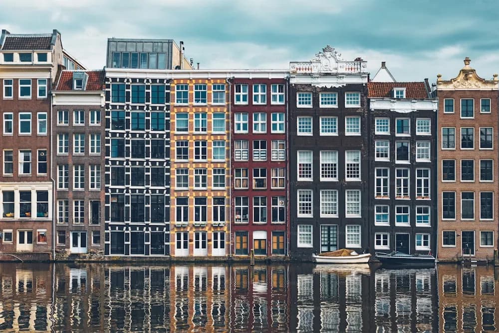 Casas estreitas refletidas em um canal de Amsterdã, com um barco atracado