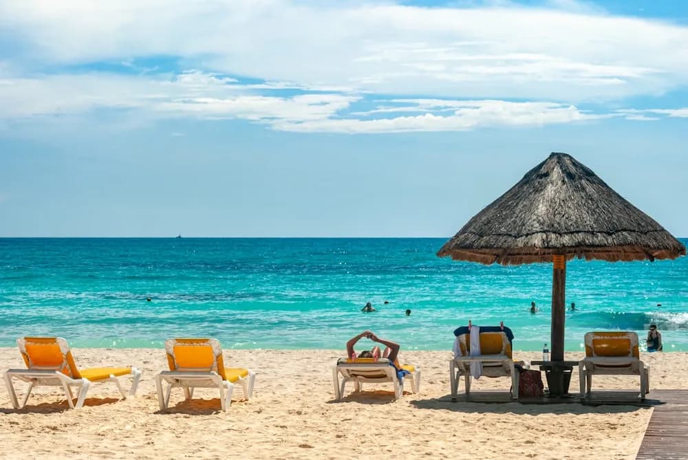 Praia de areia branca e mar turquesa com quiosque de palha em Cancún