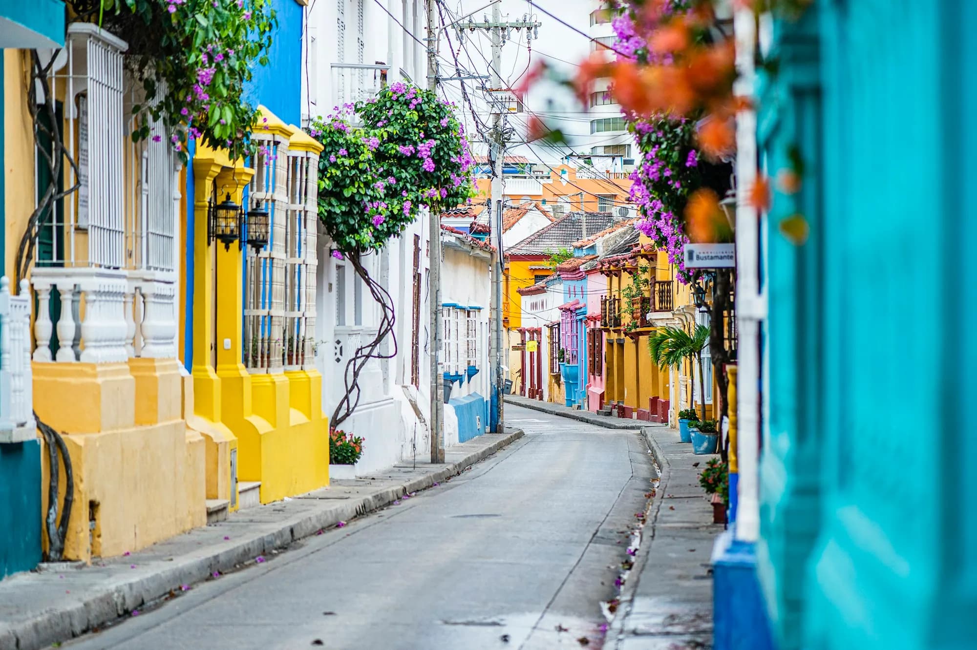 Rua da cidade amuralhada de Cartagena com fachadas coloridas e sacadas floridas