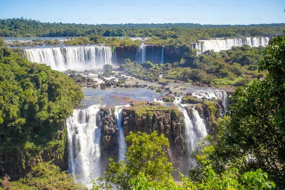 Cataratas do Iguaçu cercadas de mata sob o céu azul
