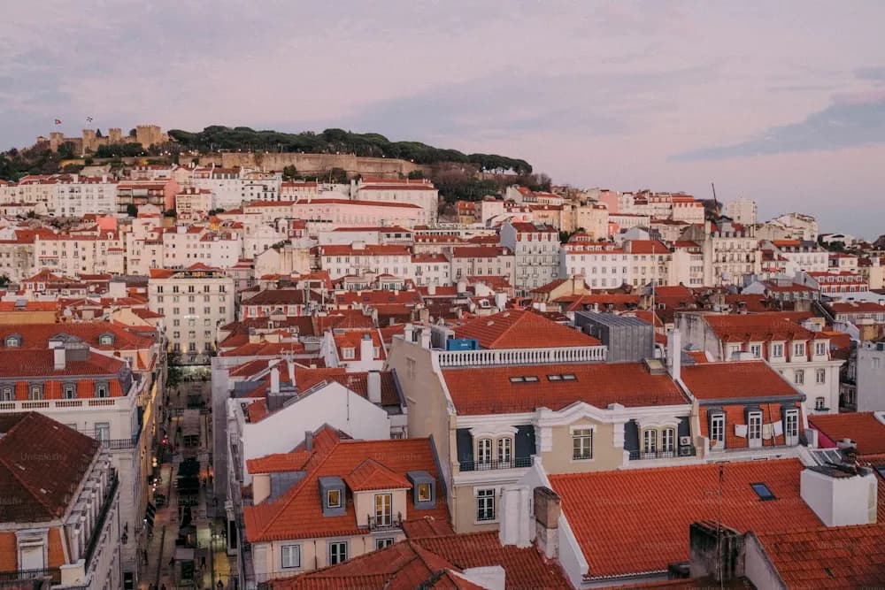Telhados alaranjados da Alfama descendo até o rio Tejo, em Lisboa