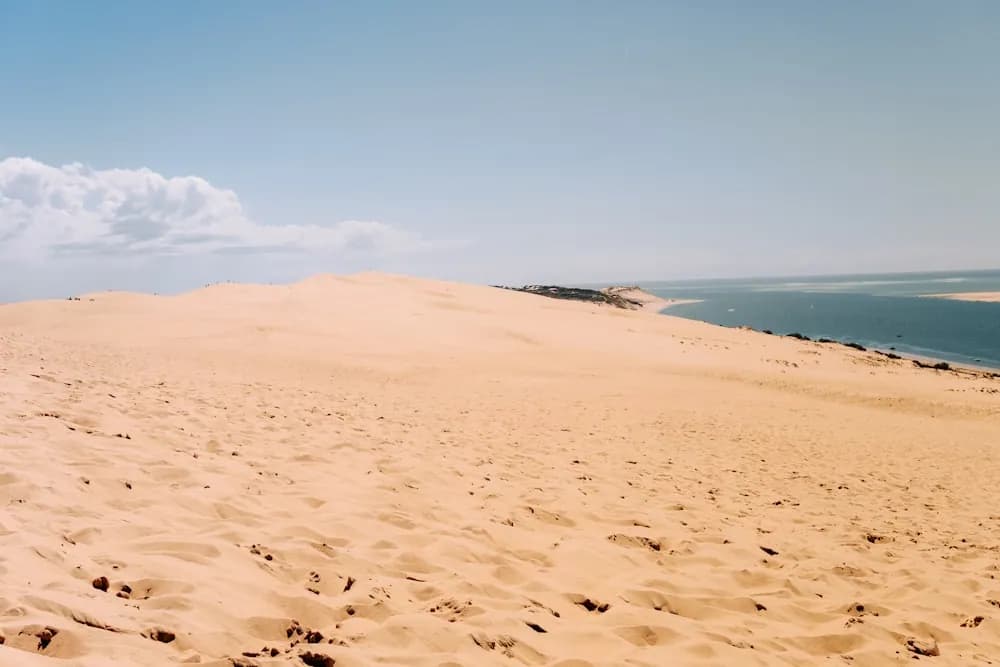 Dunas de areia encontrando o mar sob céu azul