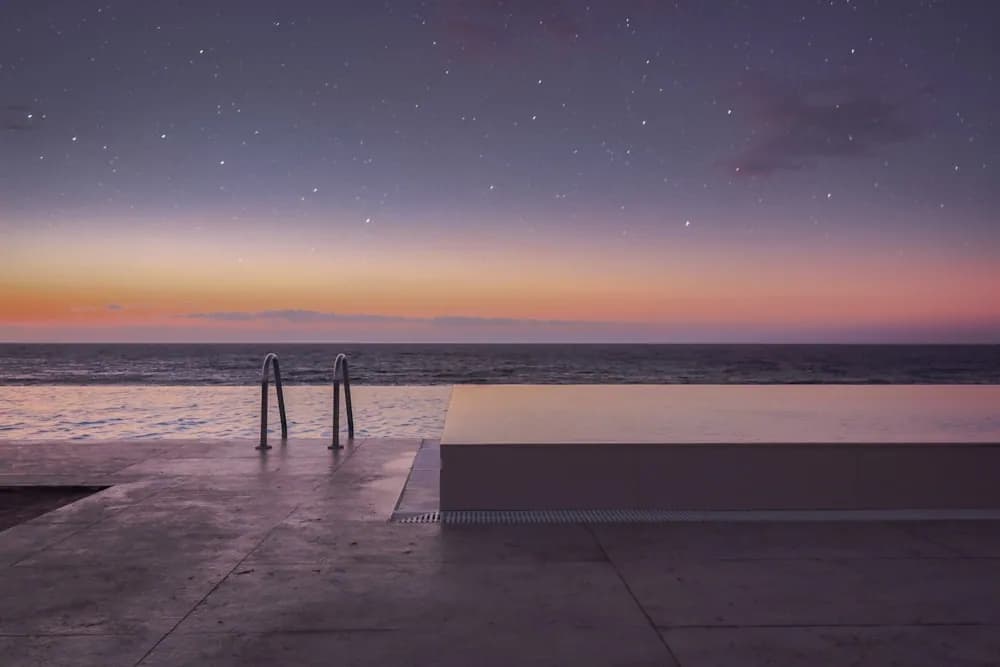 Piscina de borda infinita voltada para o mar sob céu estrelado