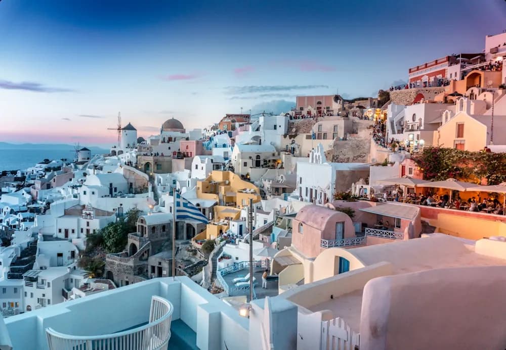 Casas brancas de cúpula azul debruçadas sobre o mar, em Santorini